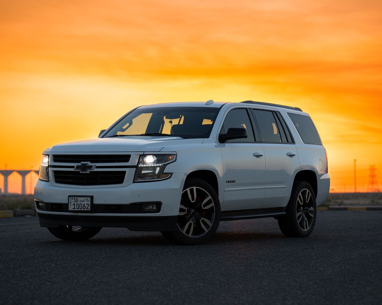 A white SUV parked on a deserted road with a vivid sunset in the background.