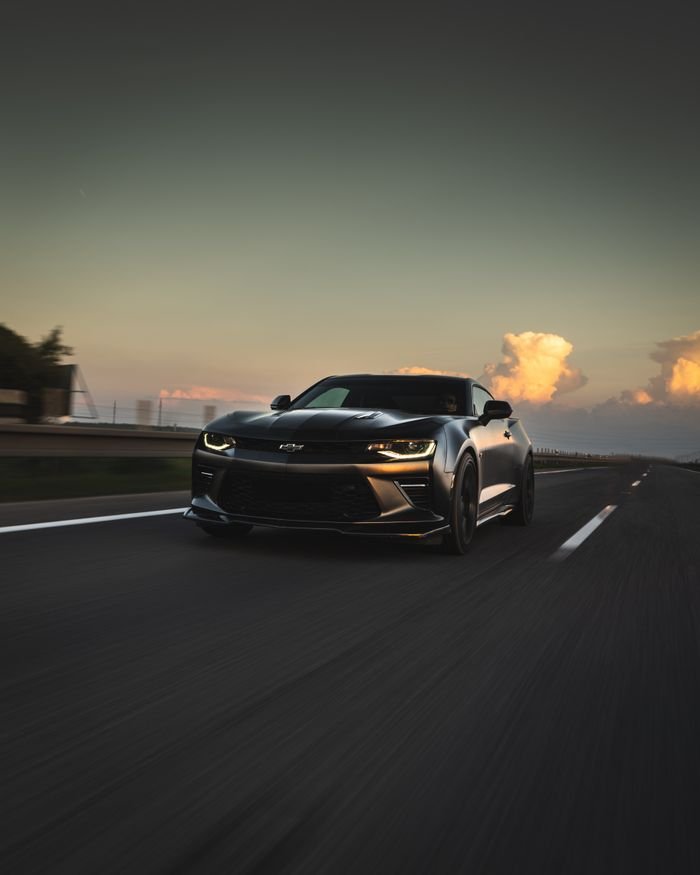 Dynamic shot of a Chevrolet Camaro driving on a scenic highway in Slovakia at sunset.